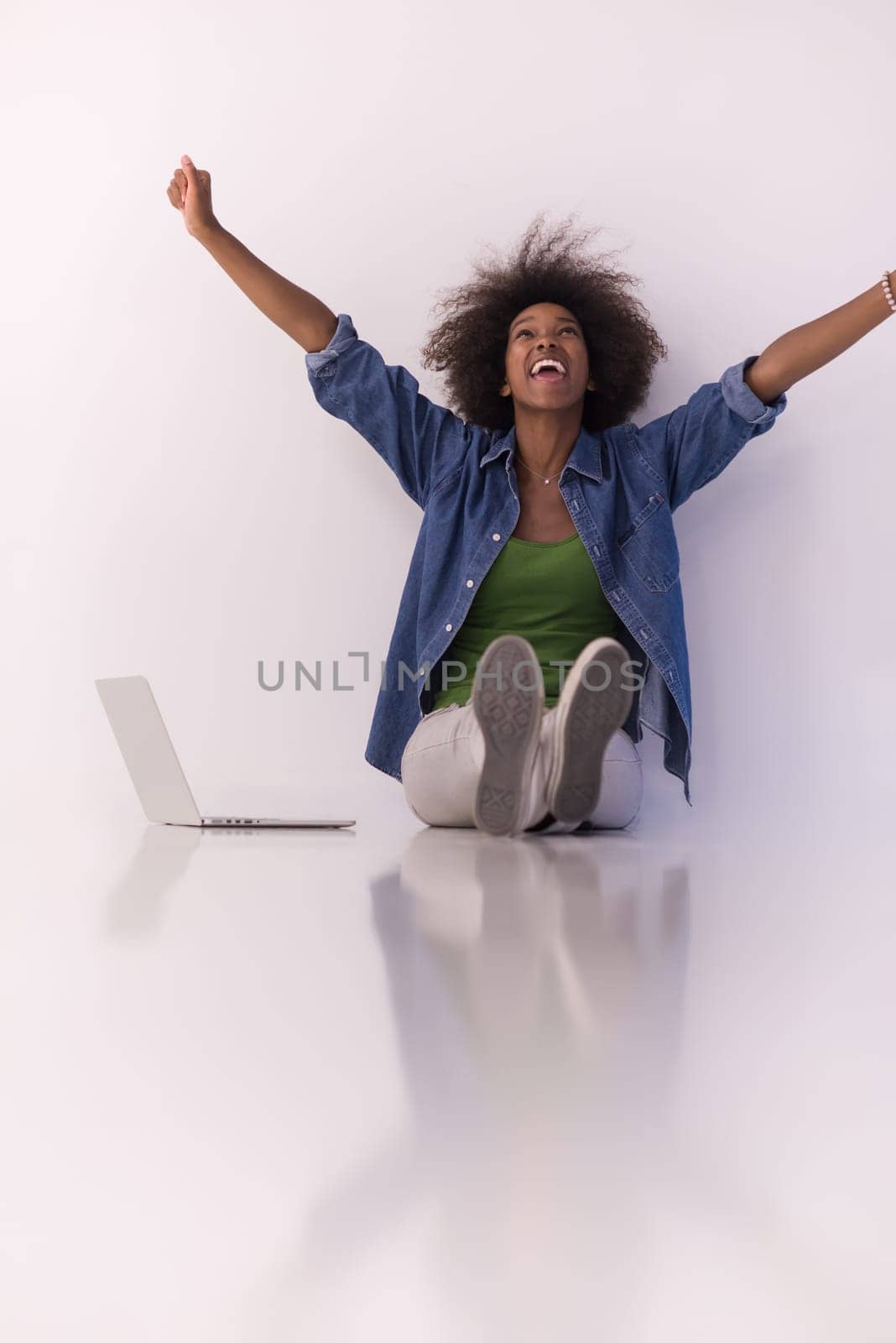 Portrait of happy young african american woman sitting on floor with laptop