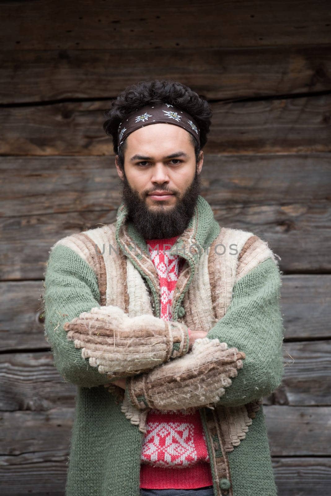 portrait of young hipster,  man with beard in front of old vintage wooden house