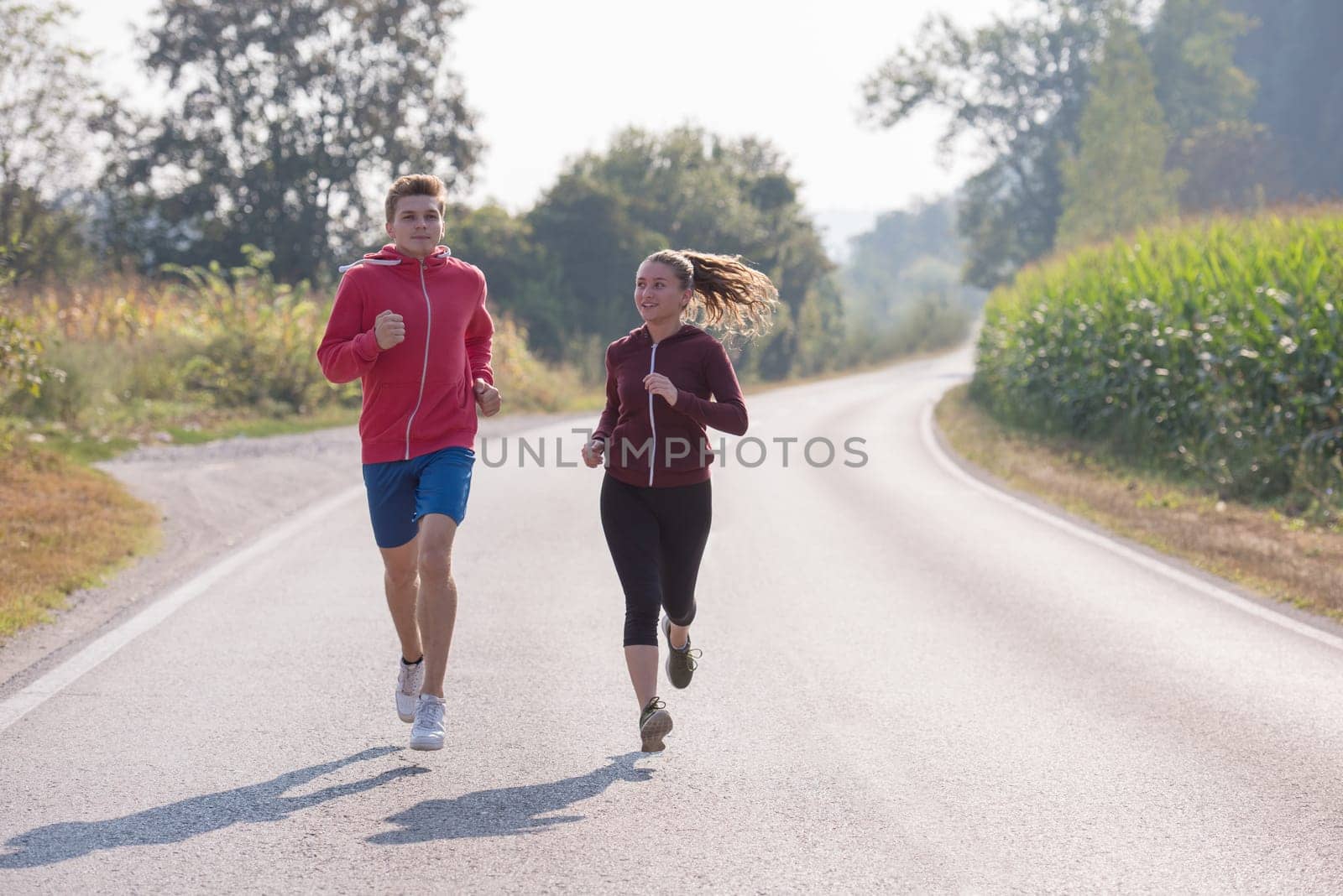young couple enjoying in a healthy lifestyle while jogging along a country road, exercise and fitness concept