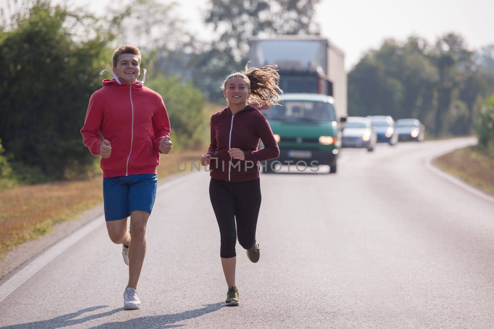 young couple enjoying in a healthy lifestyle while jogging along a country road, exercise and fitness concept