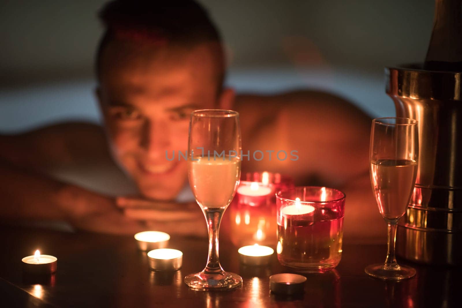 young handsome man enjoys relaxing in the jacuzzi with candles and champagne at luxury resort spa