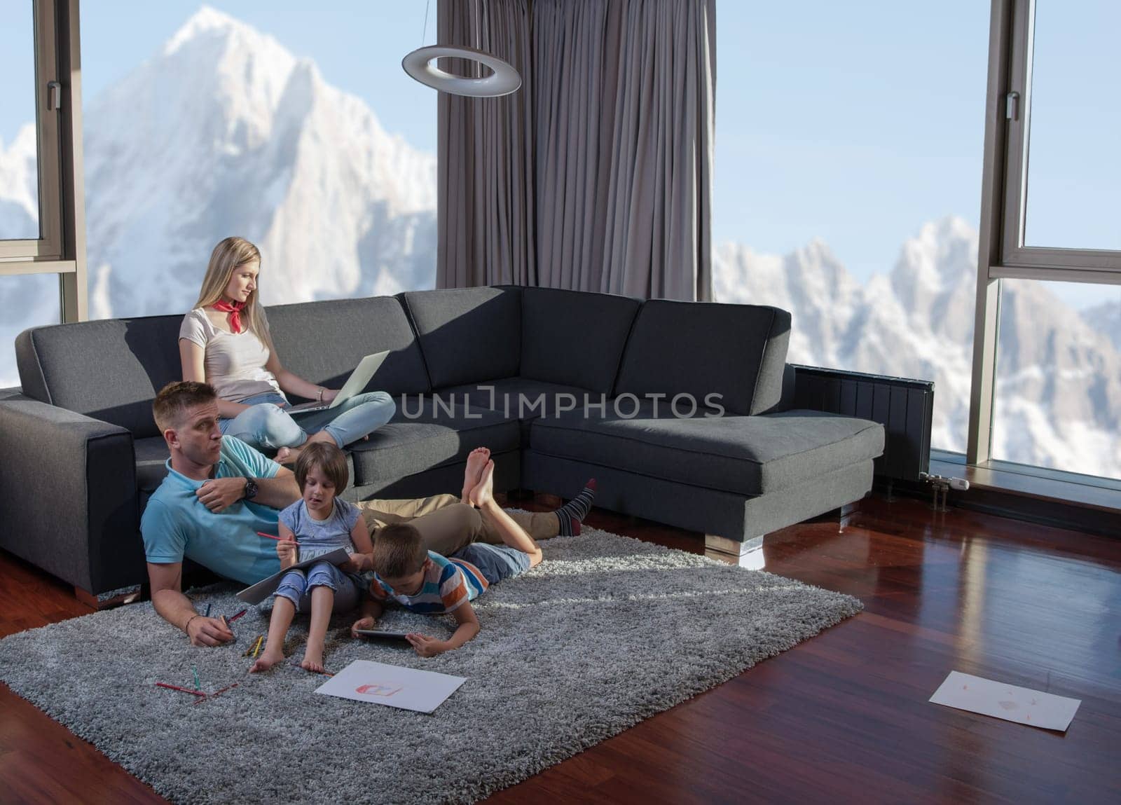 Happy Young Family Playing Together at home on the floor using a laptop computer and a children's drawing set