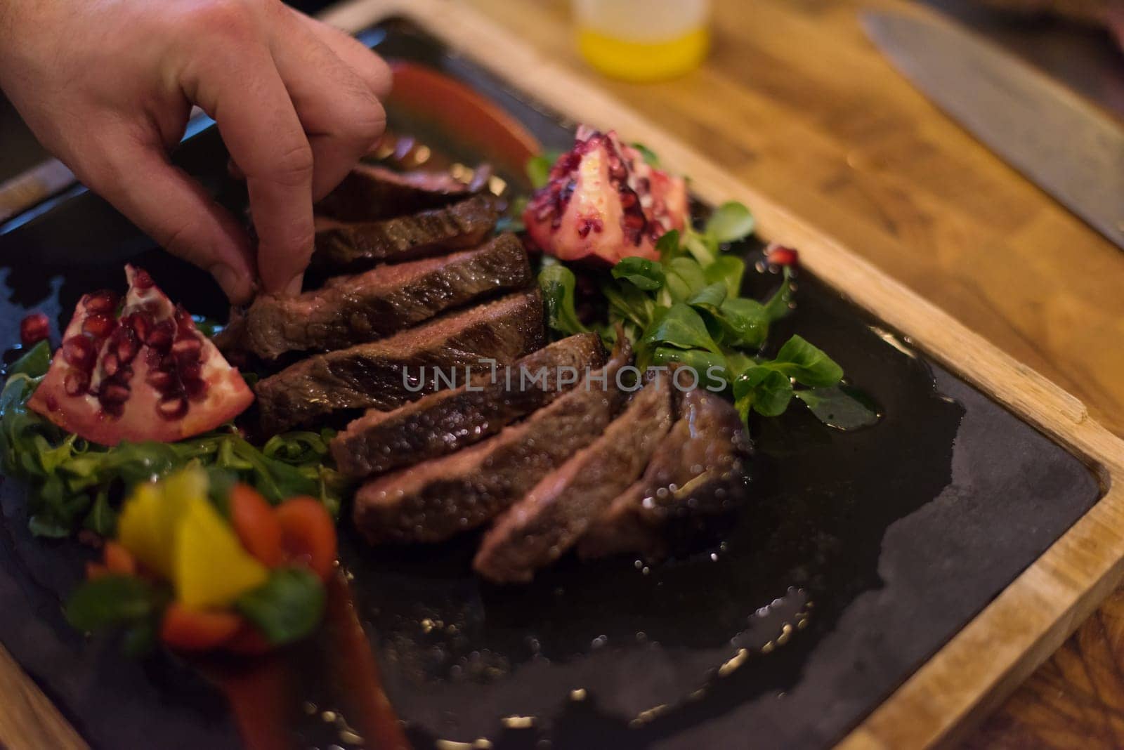 closeup of Chef hands in hotel or restaurant kitchen preparing beef steak with vegetable decoration