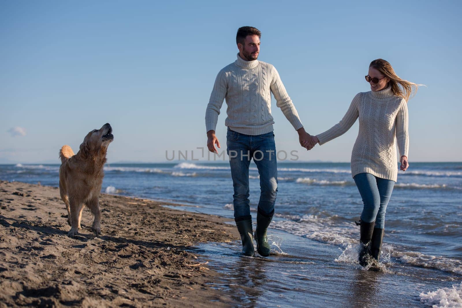 Couple Running On The Beach Holding Their Hands with dog On autmun day