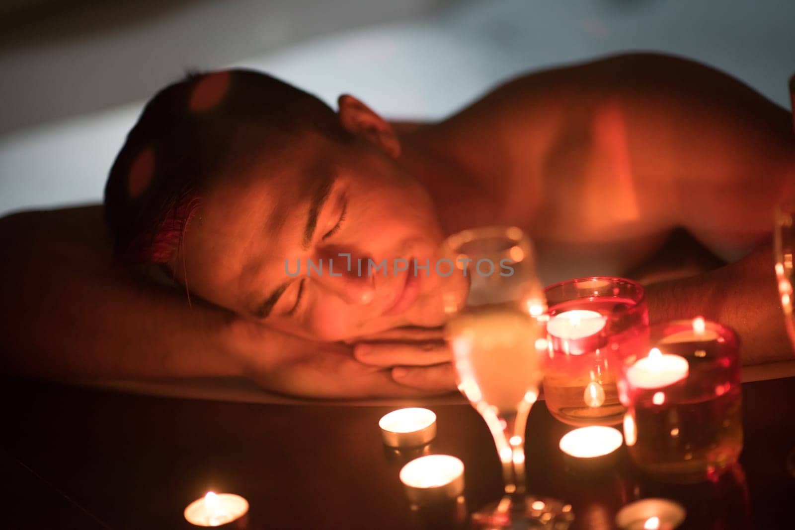 young handsome man enjoys relaxing in the jacuzzi with candles and champagne at luxury resort spa