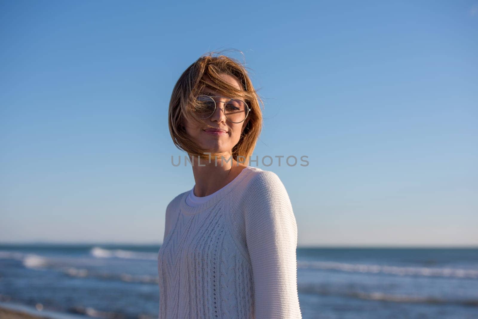 Young woman on the beach. The girl enjoying the warm autumn day. Portrait of beautiful girl near the water