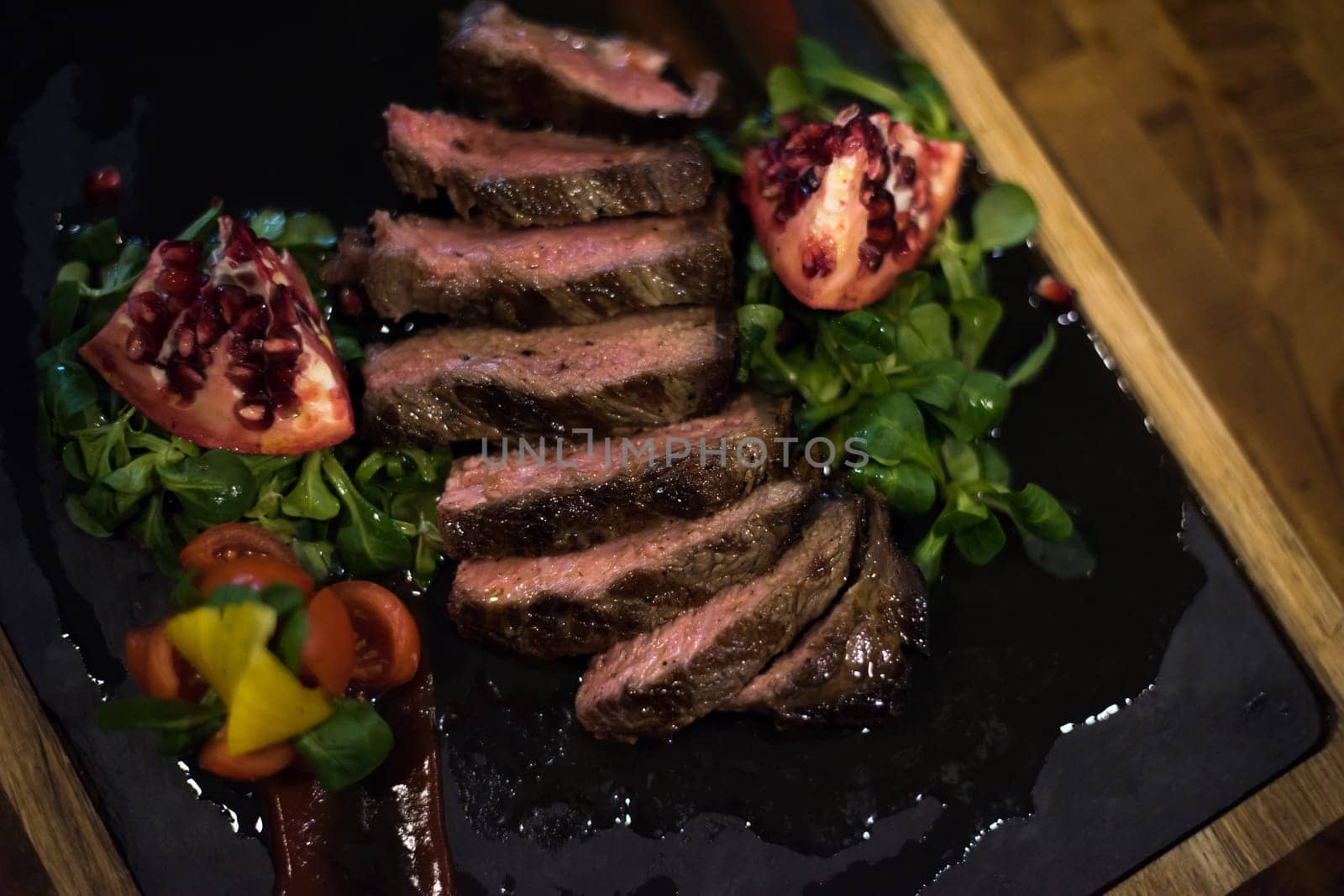 Juicy slices of grilled steak  with vegetables on a wooden board