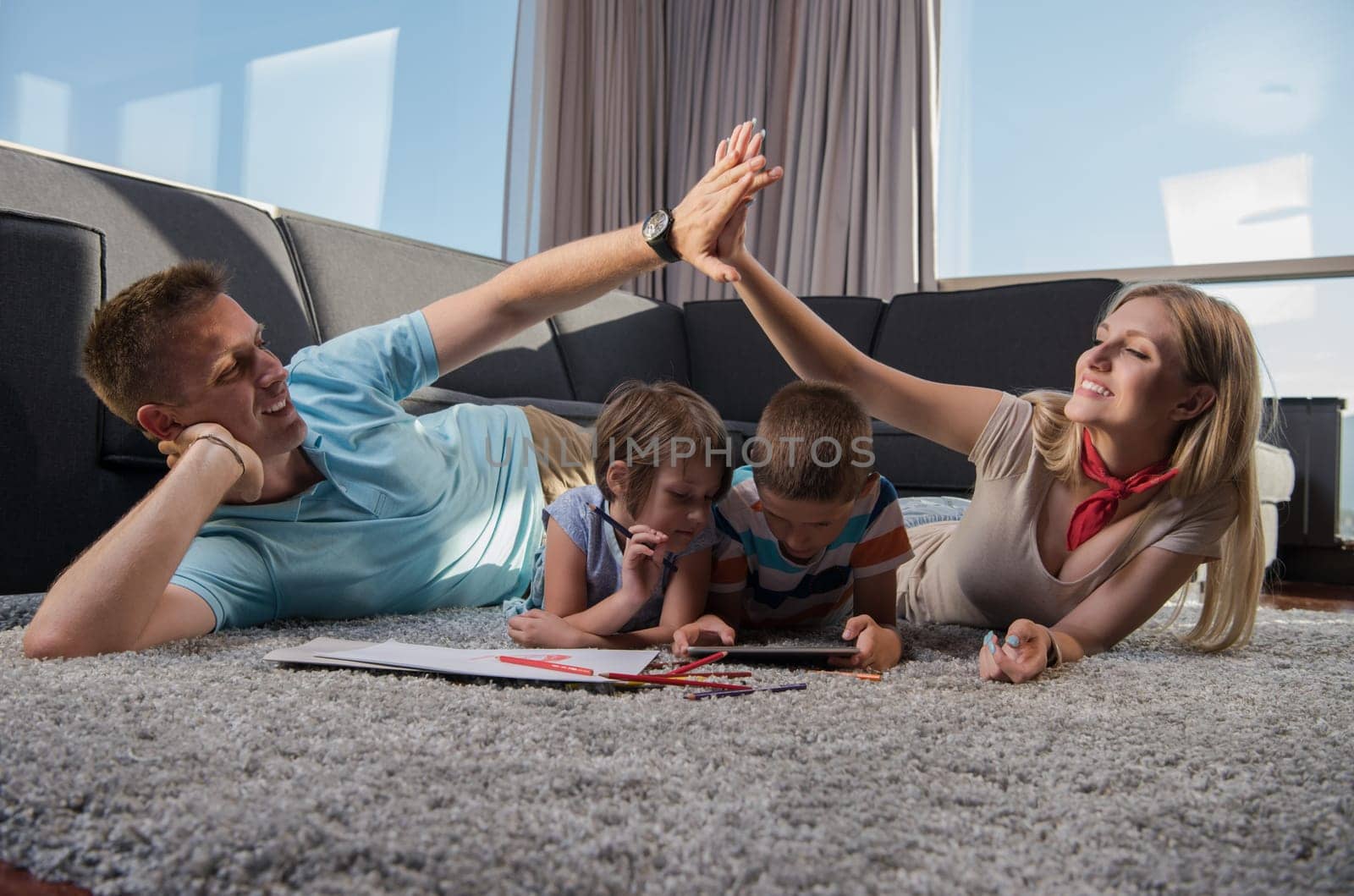 Happy Young Family Playing Together at home on the floor using a tablet and a children's drawing set