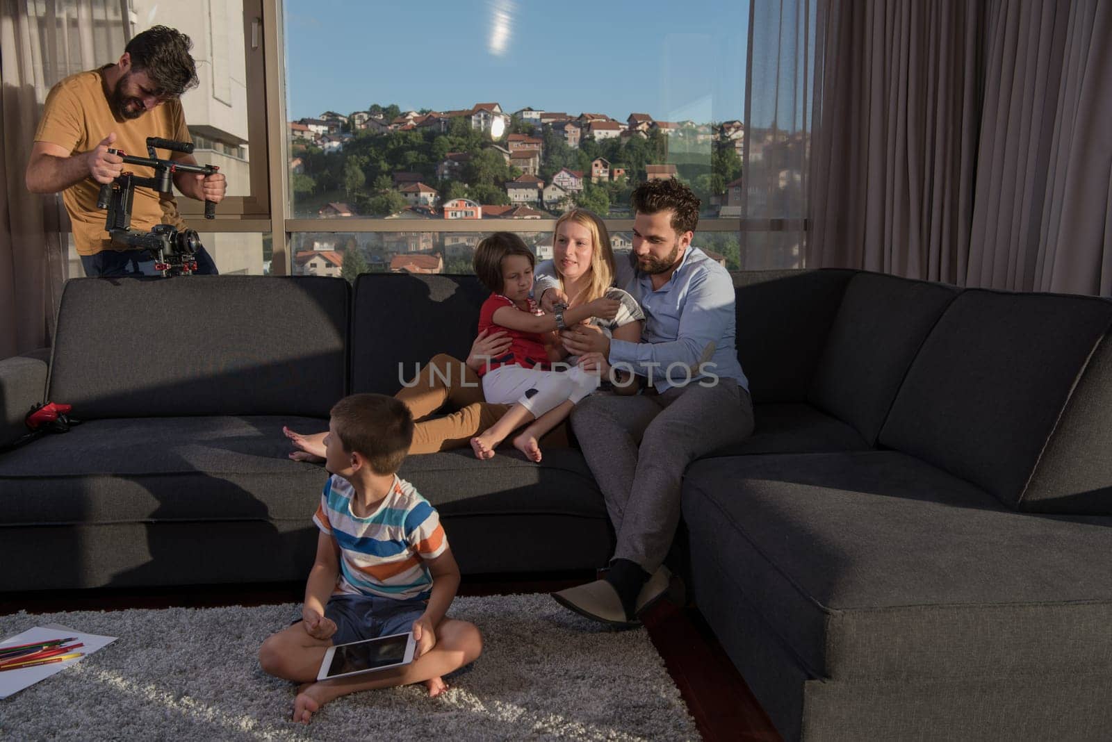 happy couple spending time with kids using tablet computer on sofa at home