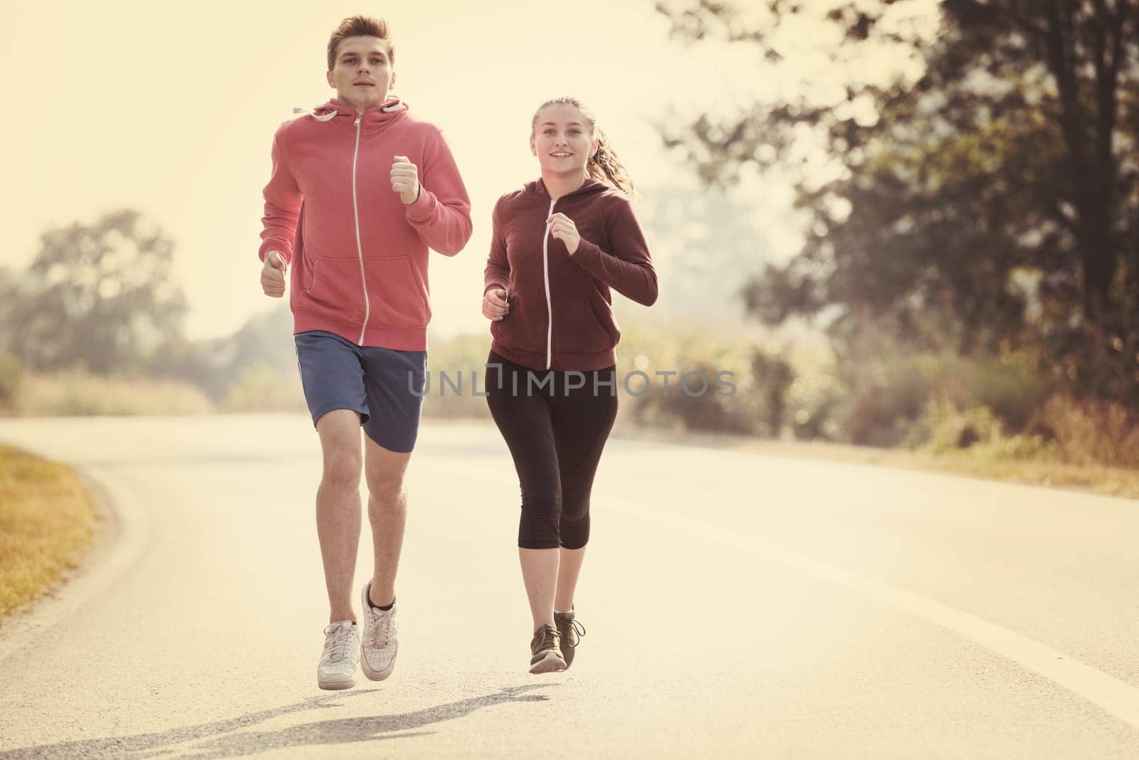 young couple enjoying in a healthy lifestyle while jogging along a country road, exercise and fitness concept