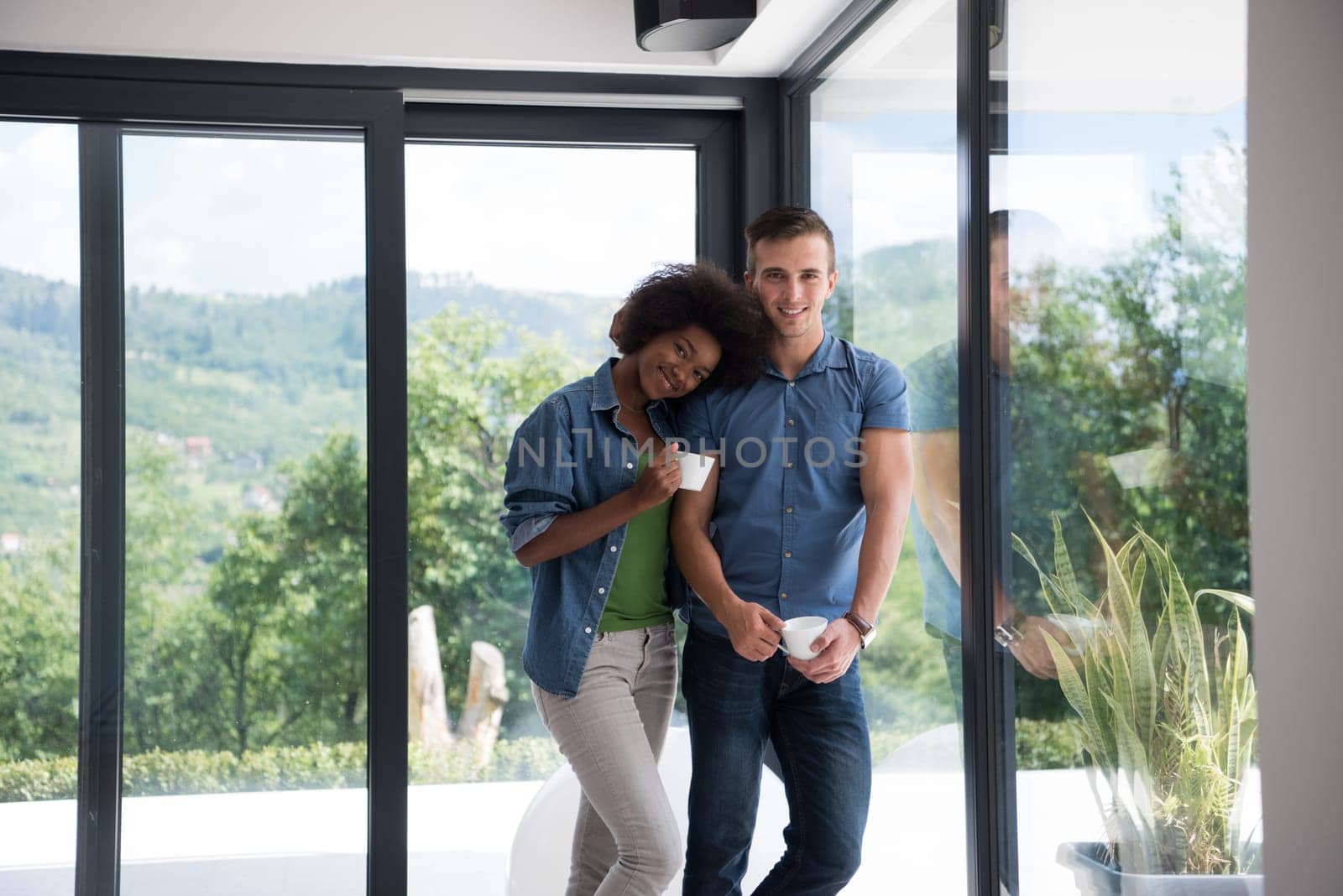 romantic happy young multiethnic couple enjoying morning coffee by the window in their luxury home