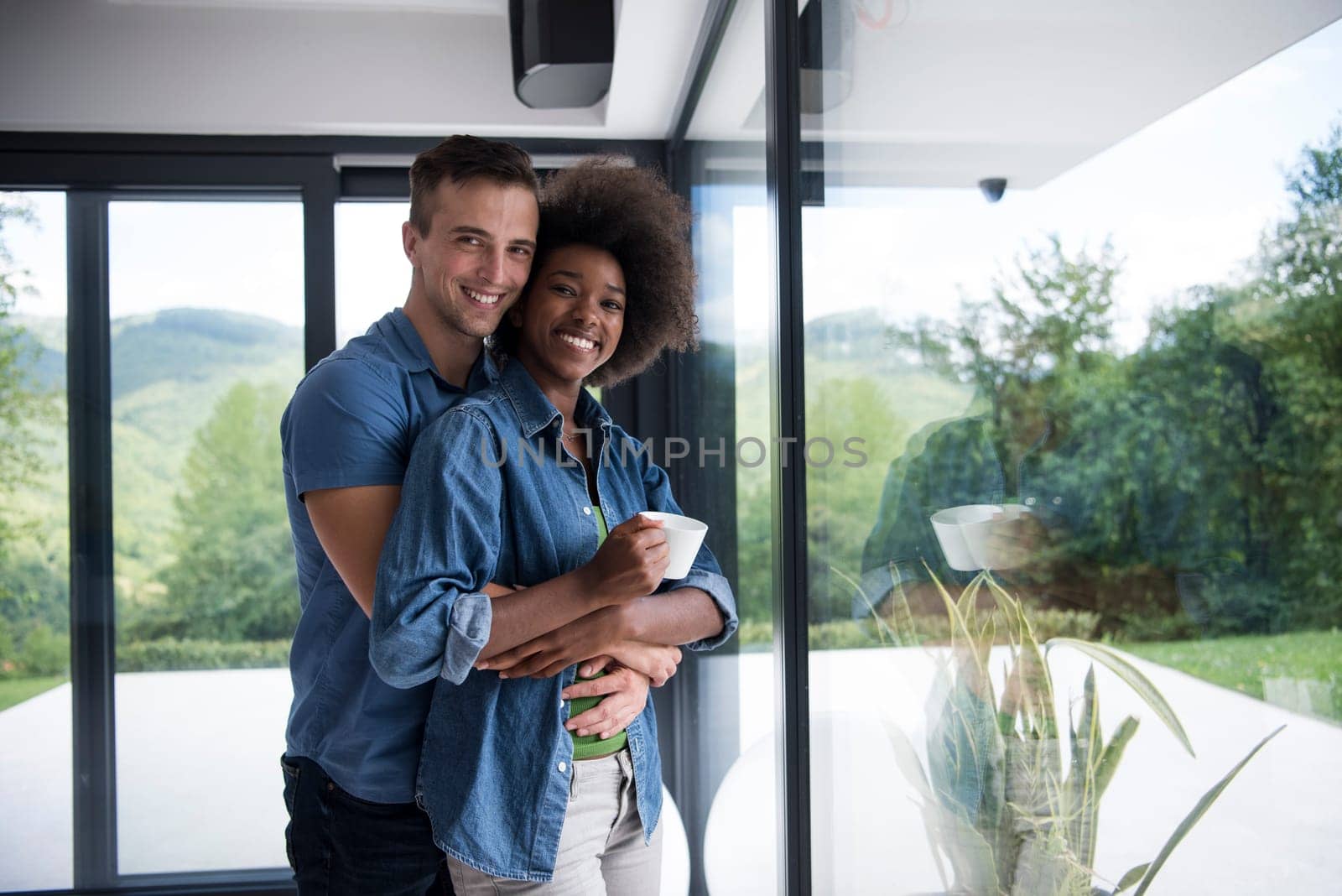 romantic happy young multiethnic couple enjoying morning coffee by the window in their luxury home