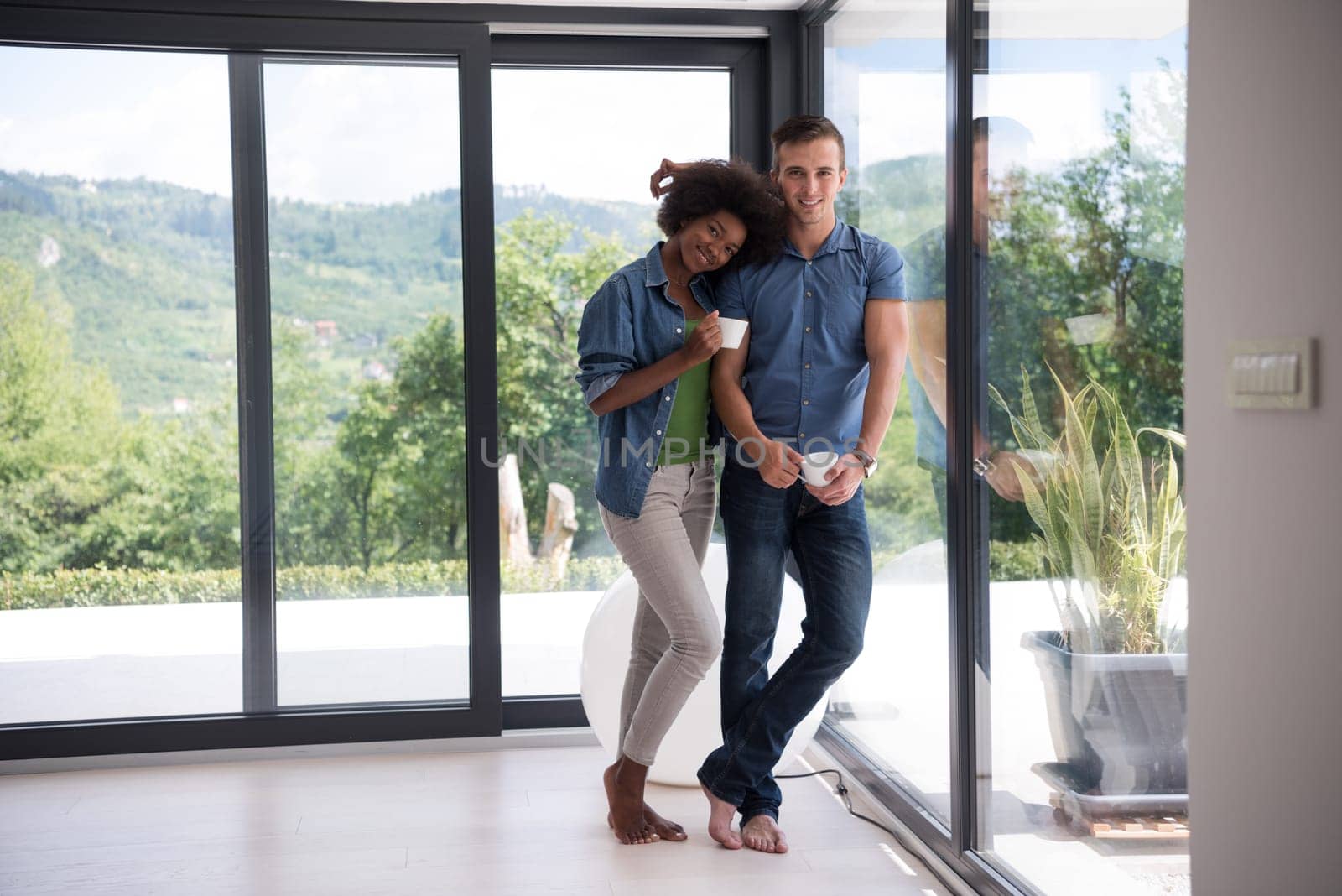 romantic happy young multiethnic couple enjoying morning coffee by the window in their luxury home
