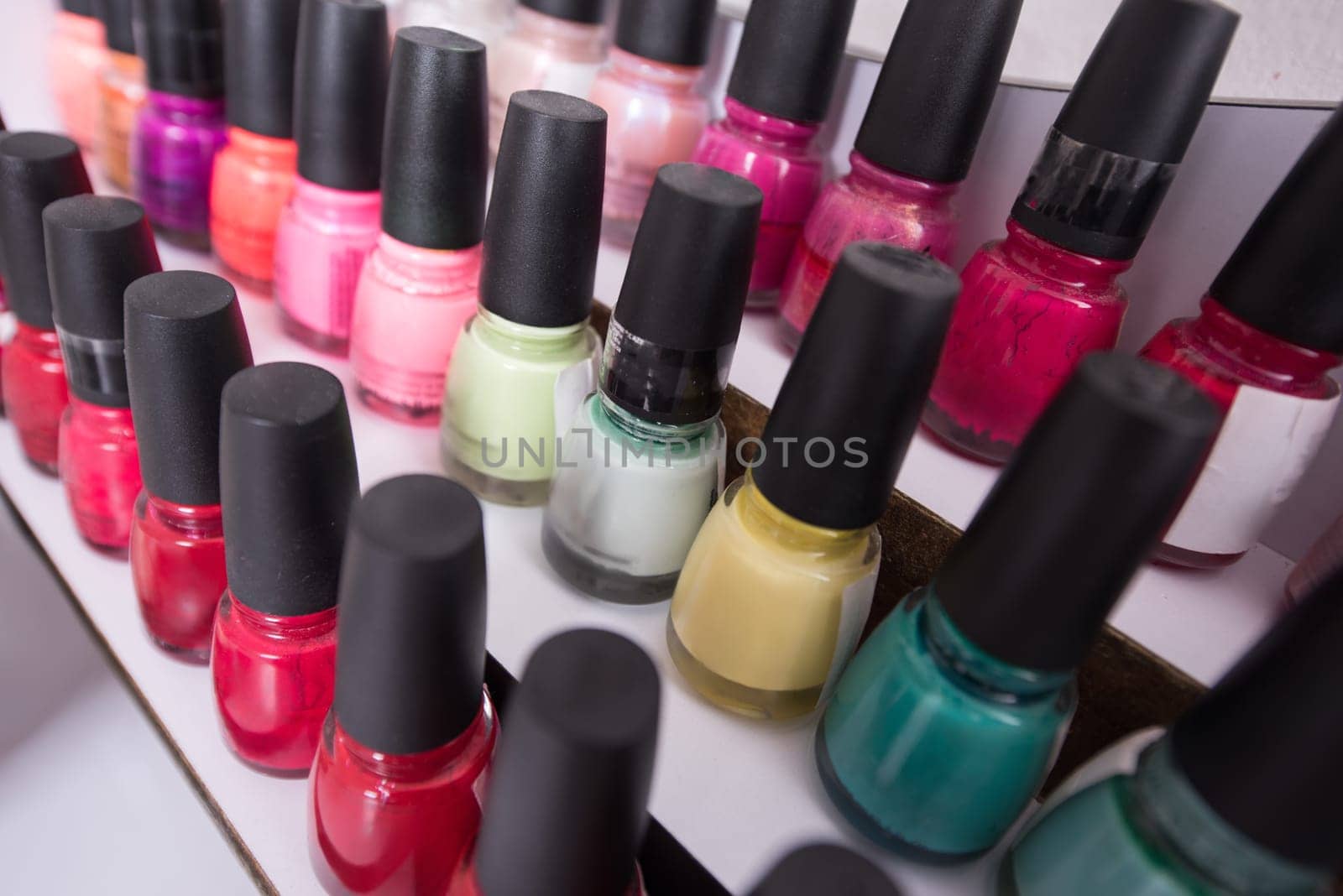 Set of different bottles of nail polish in the shelf in the beauty salon