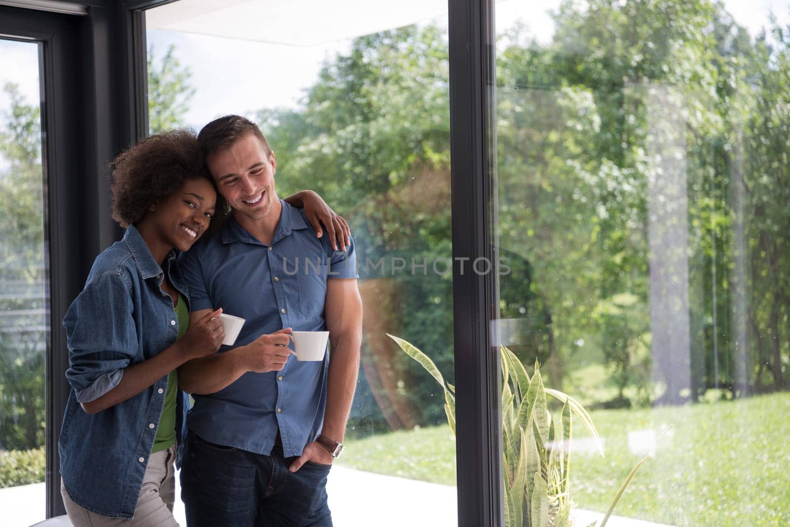 romantic happy young multiethnic couple enjoying morning coffee by the window in their luxury home