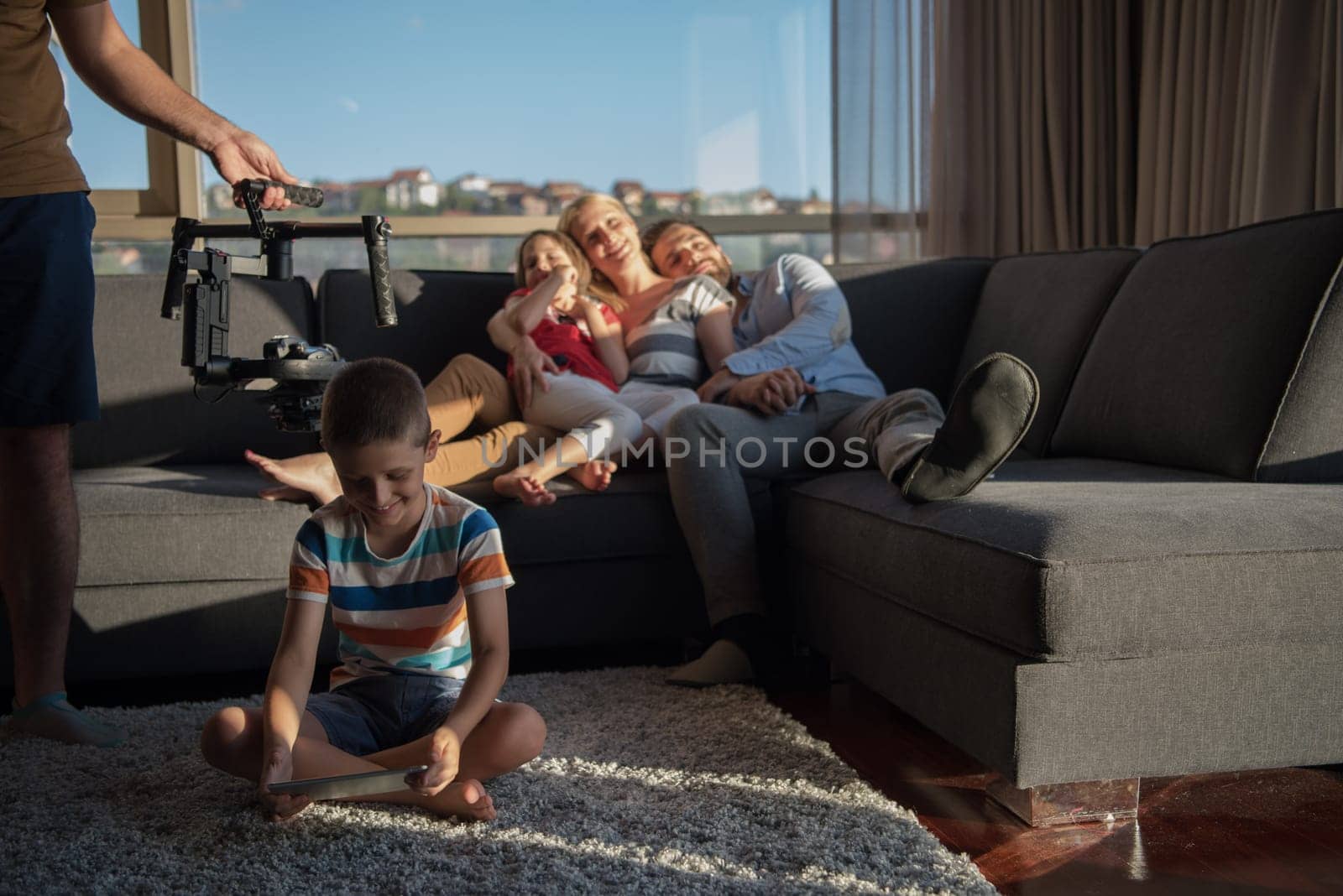 happy couple spending time with kids using tablet computer on sofa at home