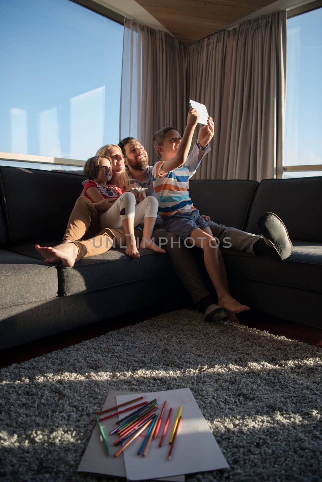 happy couple spending time with kids using tablet computer on sofa at home