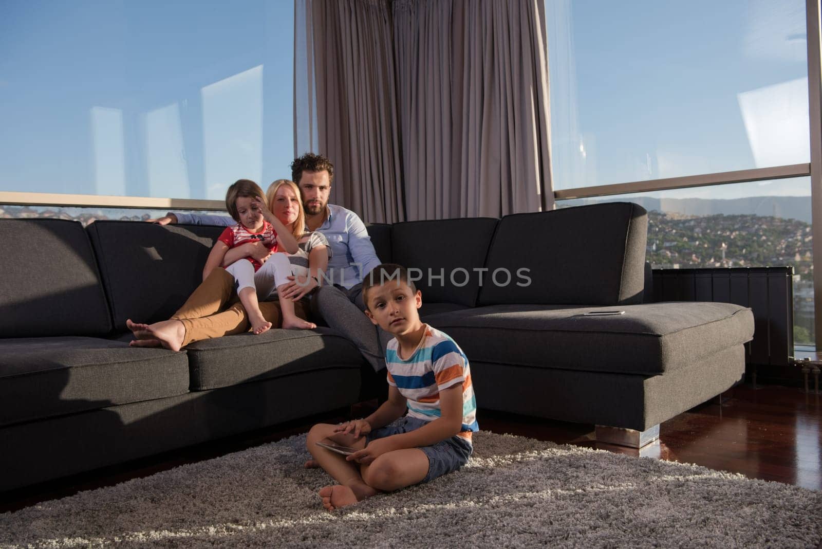 happy couple spending time with kids using tablet computer on sofa at home