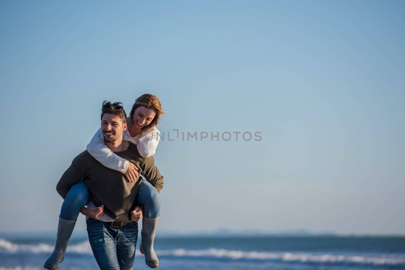 Men Giving Piggy Back Rides to his girlfriend At Sunset By The Sea, autumn time
