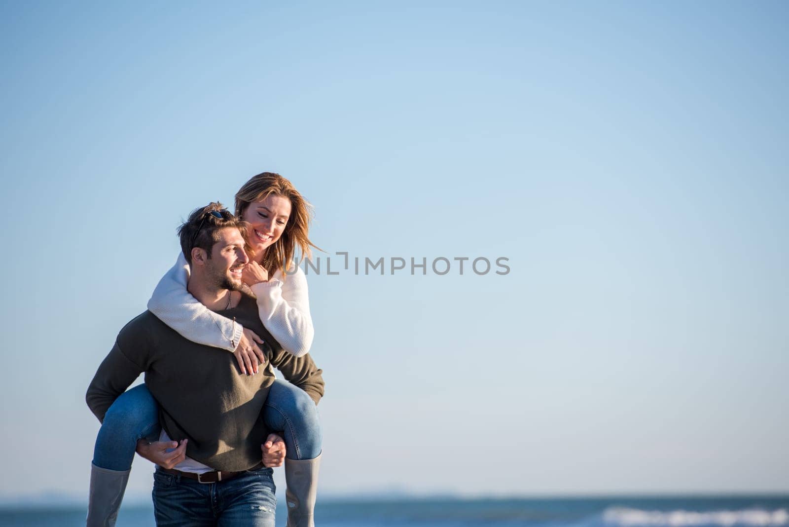 Men Giving Piggy Back Rides to his girlfriend At Sunset By The Sea, autumn time