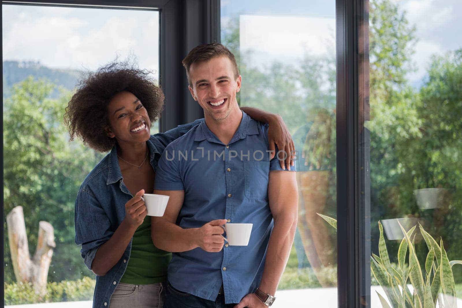 romantic happy young multiethnic couple enjoying morning coffee by the window in their luxury home