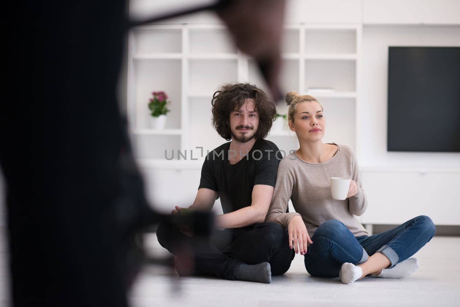 portrait of young happy beautiful couple sitting on the floor and drinking coffee in their new home