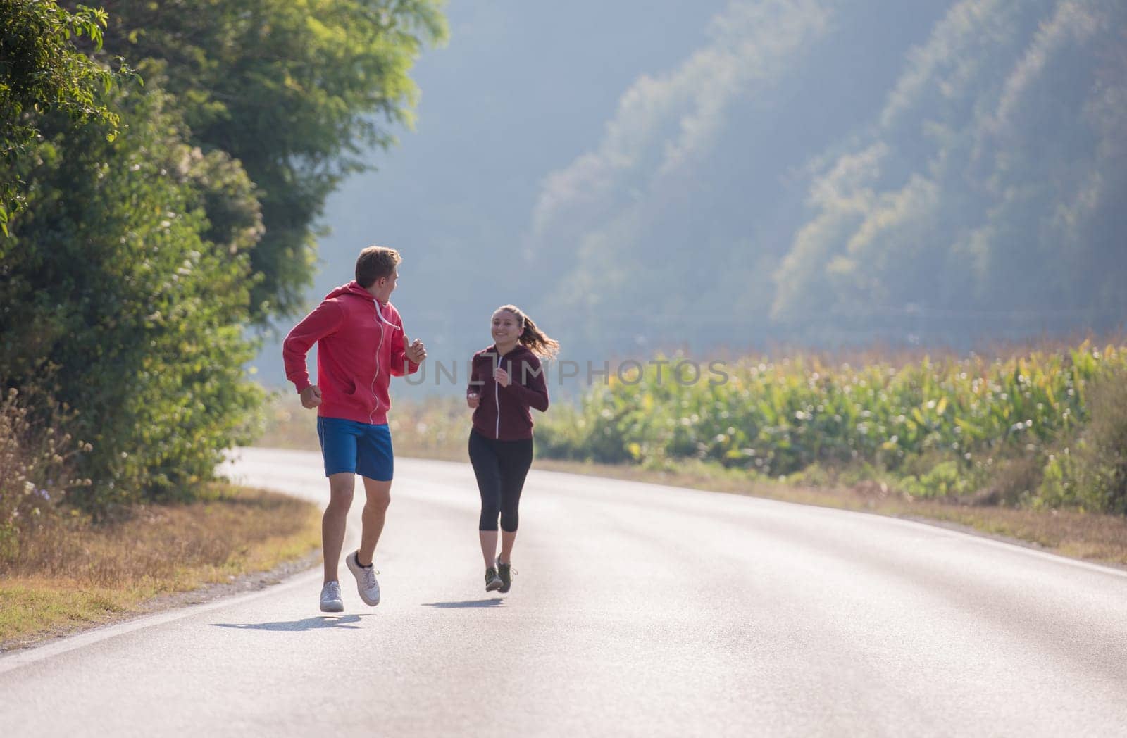 young couple enjoying in a healthy lifestyle while jogging along a country road, exercise and fitness concept