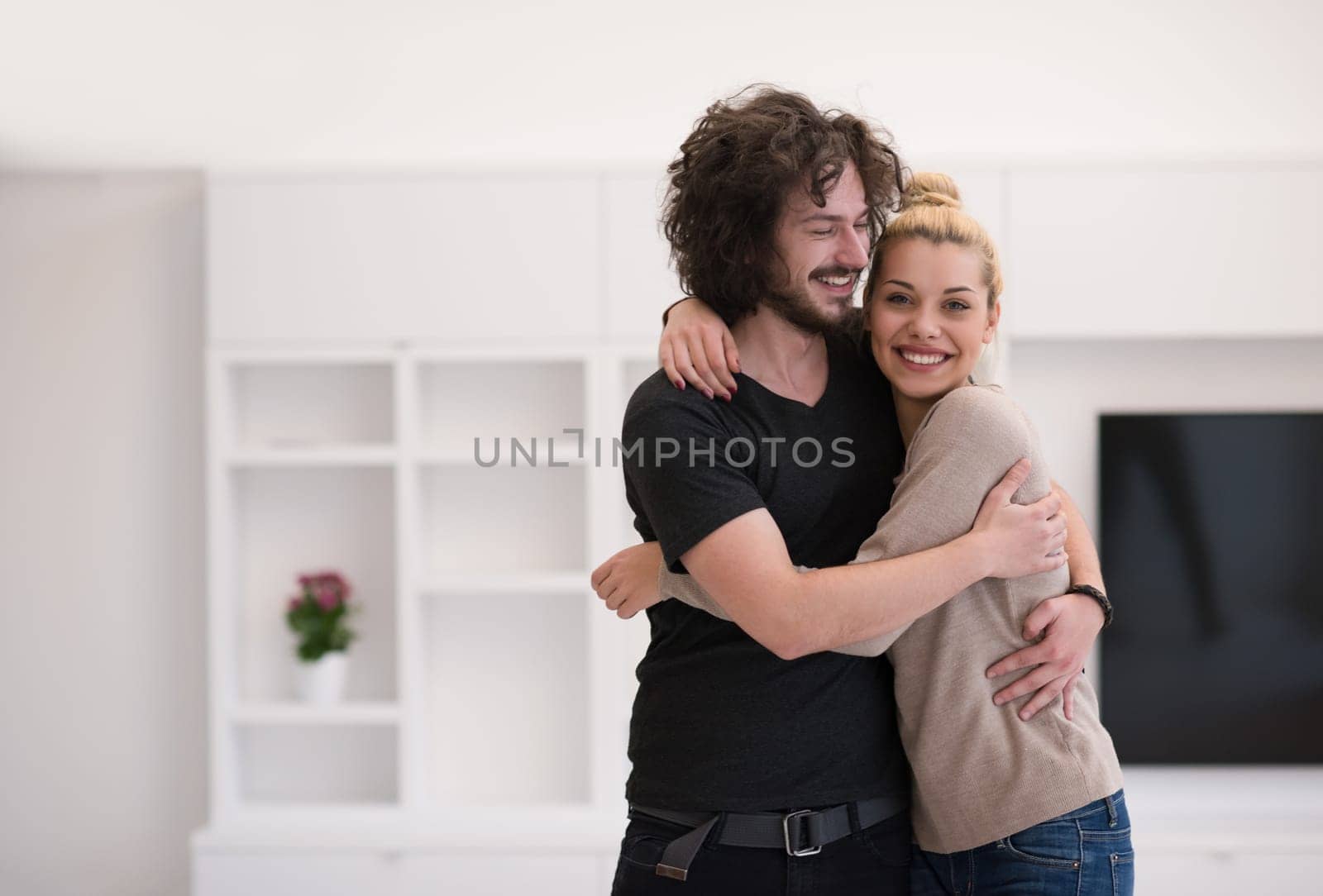 Portrait of a happy young beautiful couple hugging in their new home