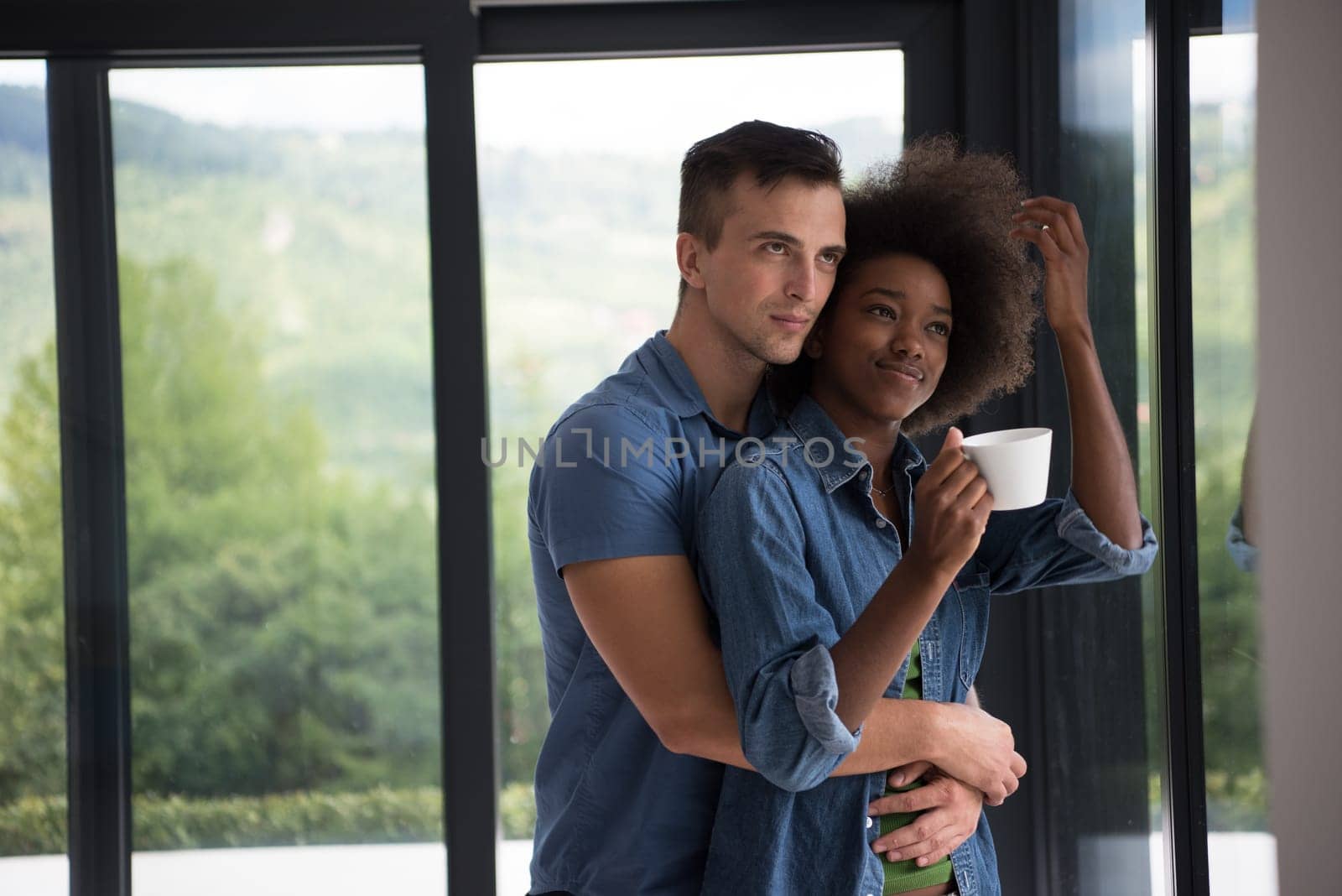 romantic happy young multiethnic couple enjoying morning coffee by the window in their luxury home