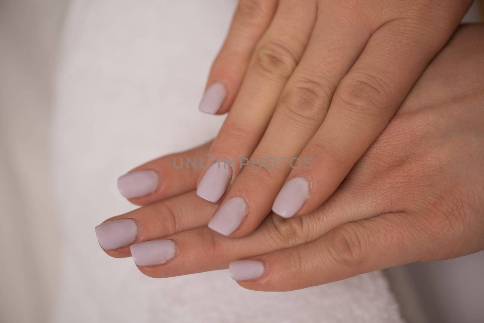 Beautiful fingers with french manicure on the towel. Manicure in a beauty salon.