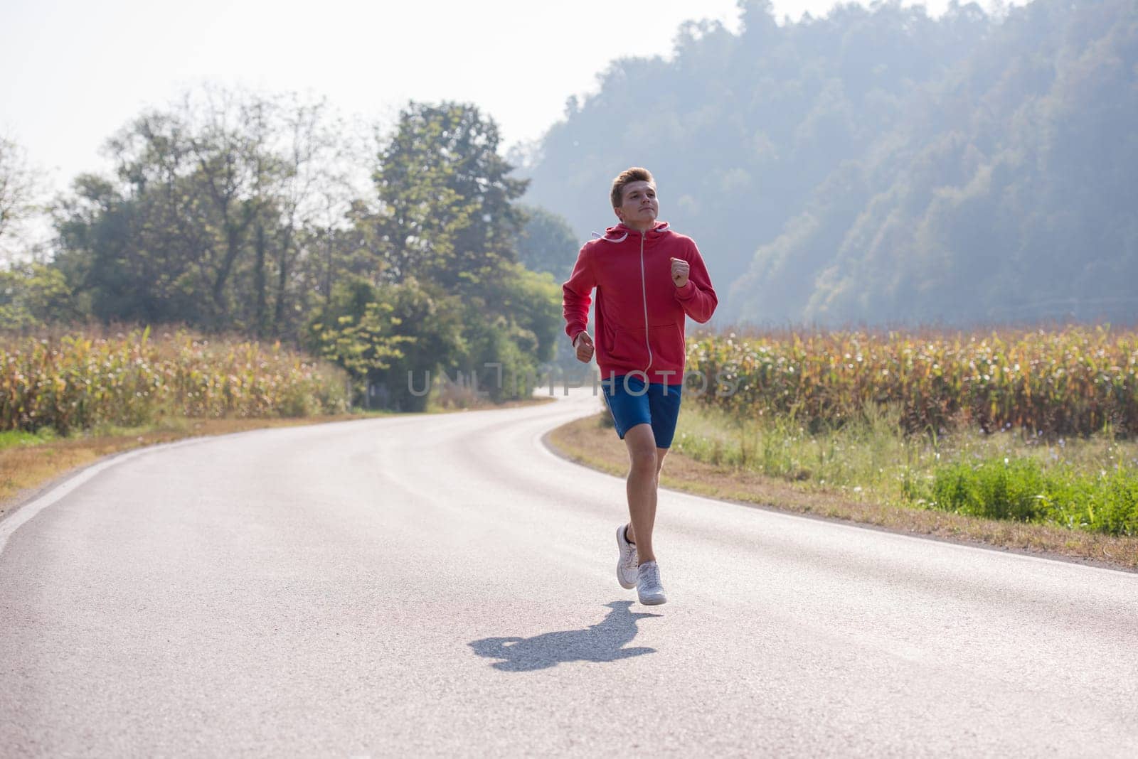 young man enjoying in a healthy lifestyle while jogging along a country road, exercise and fitness concept