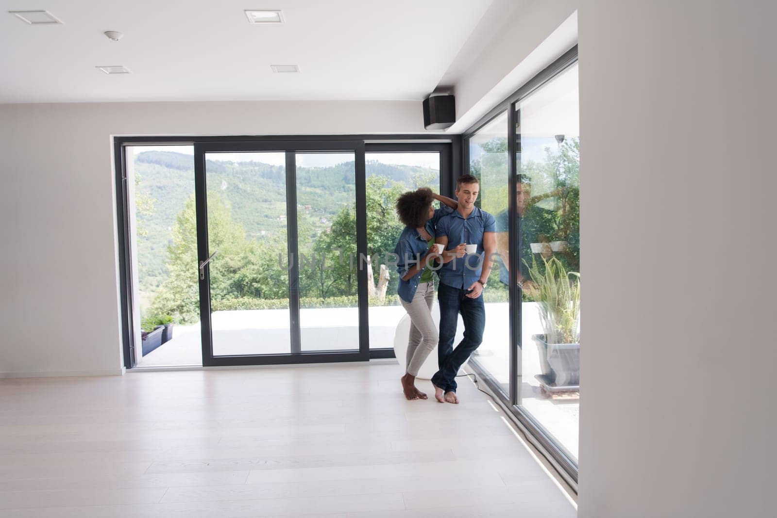 romantic happy young multiethnic couple enjoying morning coffee by the window in their luxury home