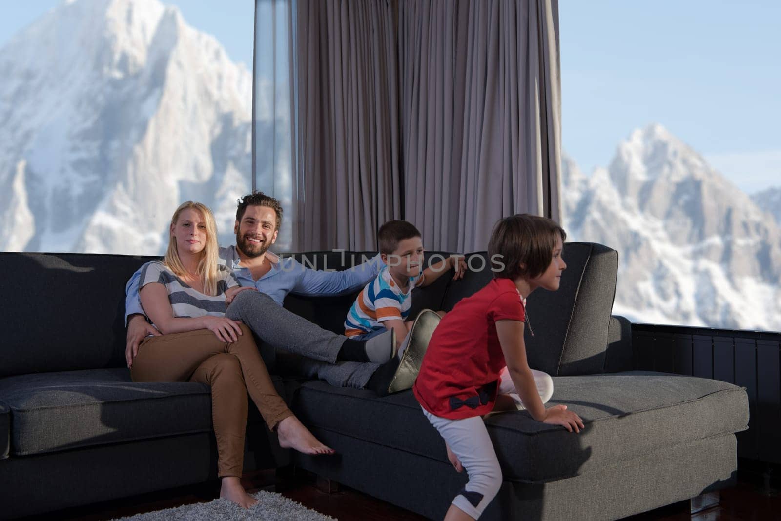 happy couple spending time with kids using tablet computer on sofa at home