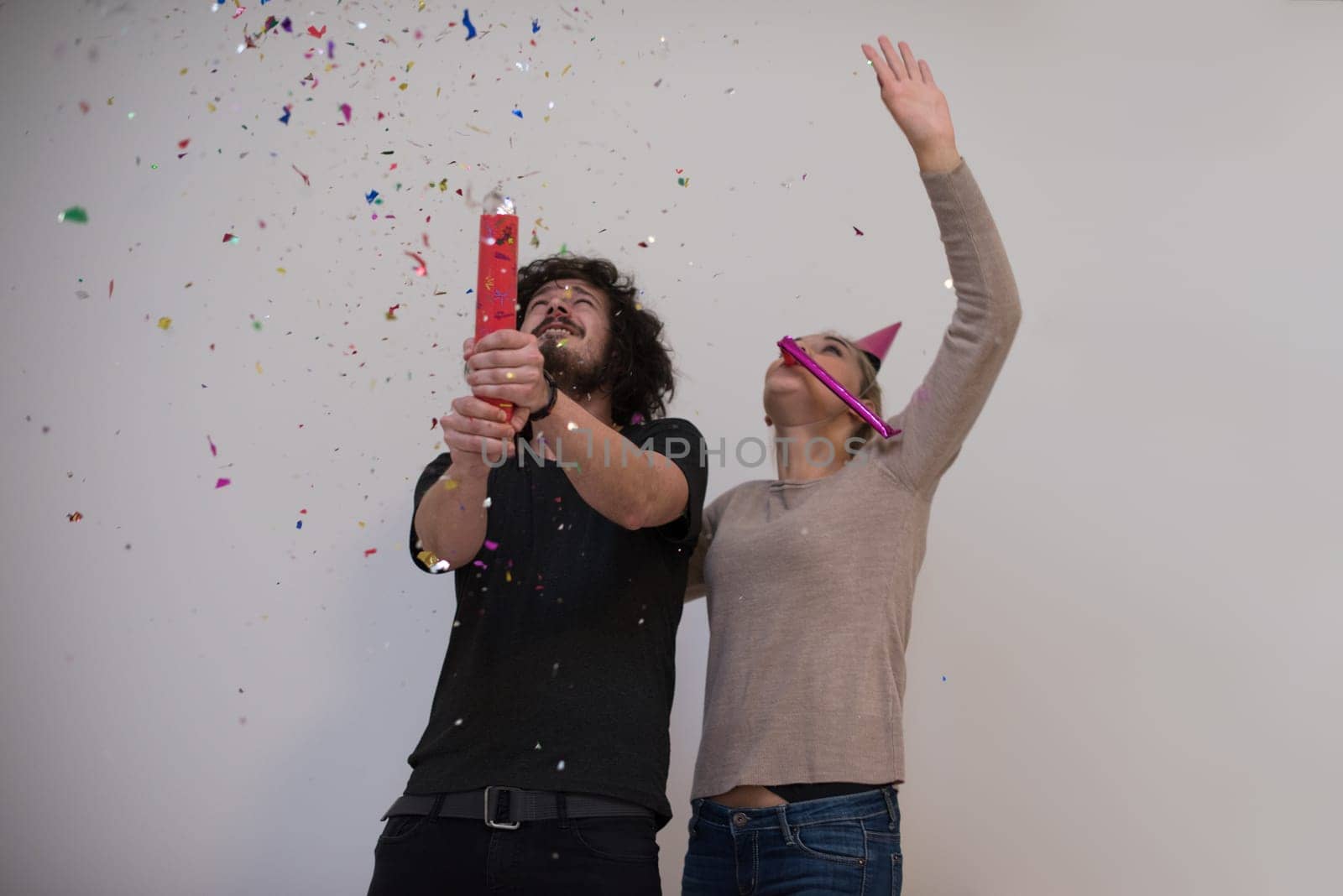 happy young romantic  couple in love  celebrating and blowing confetti decorations at new year and charismas  party