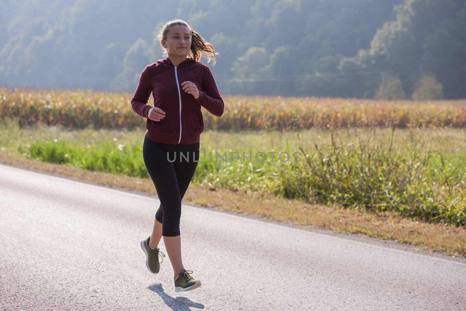 young woman enjoying in a healthy lifestyle while jogging along a country road, exercise and fitness concept
