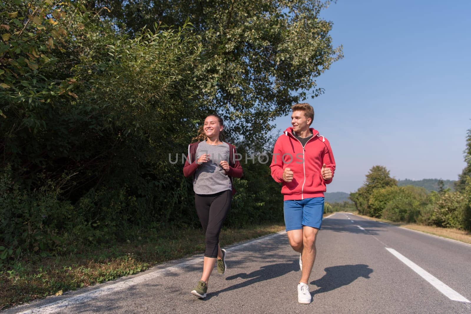 young couple enjoying in a healthy lifestyle while jogging along a country road, exercise and fitness concept