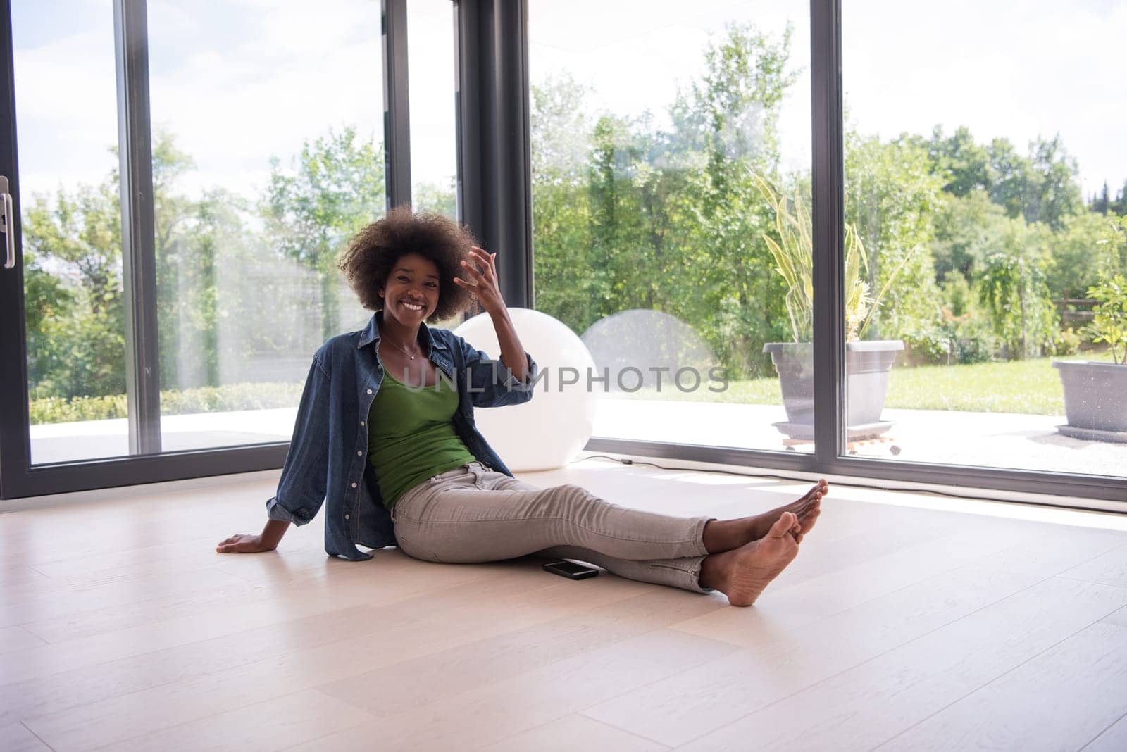 Beautiful african american young woman in casual fashion clothes sitting near window