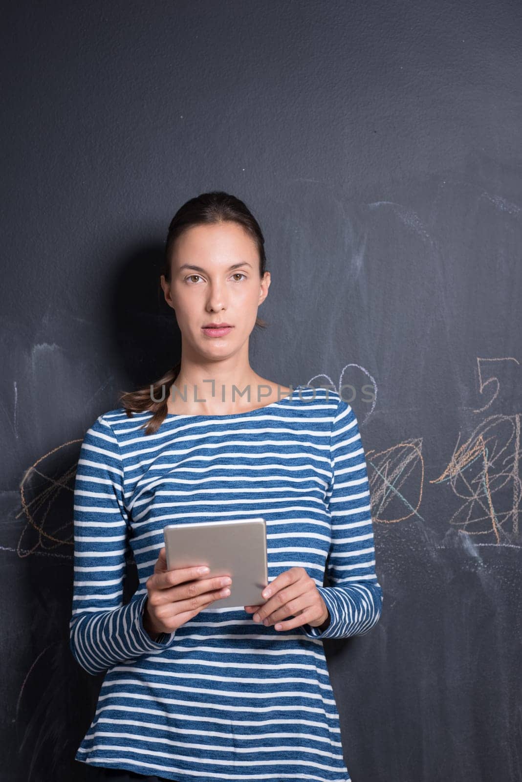Happy young woman using tablet computer in front of chalk drawing board