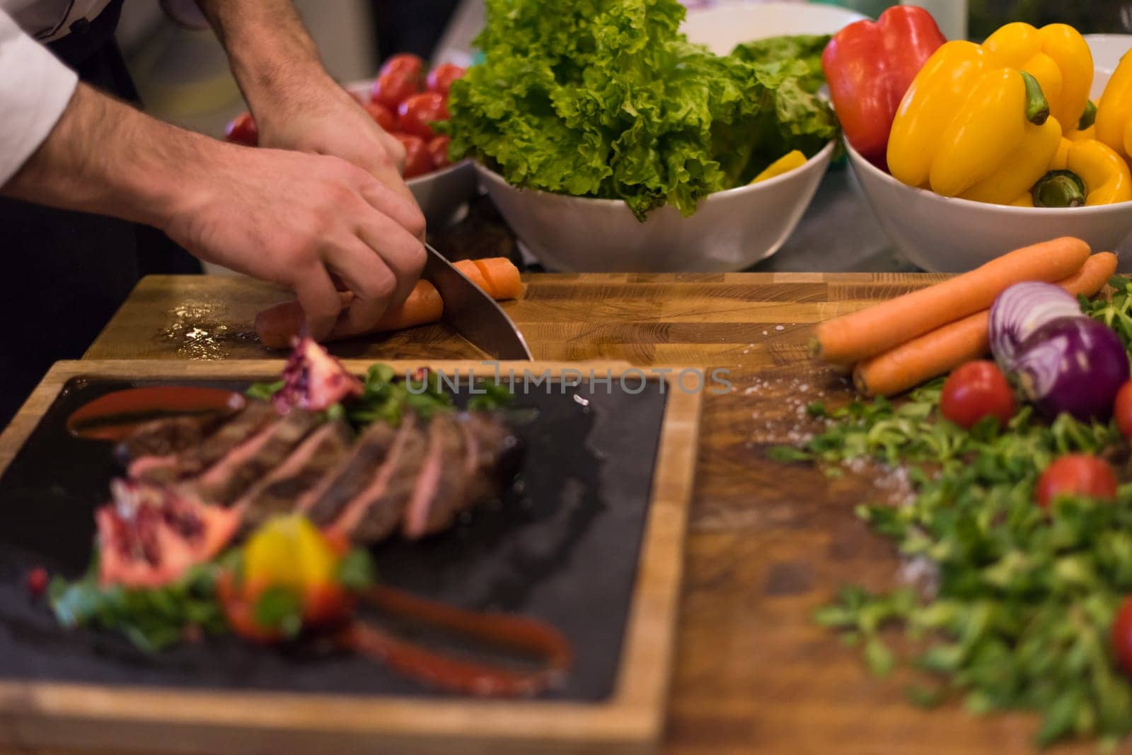 closeup of Chef hands in hotel or restaurant kitchen preparing beef steak with vegetable decoration