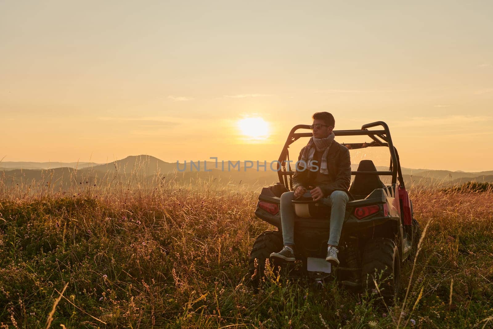 portrait of young happy excited man enjoying beautiful sunny day while driving a off road buggy car on mountain nature