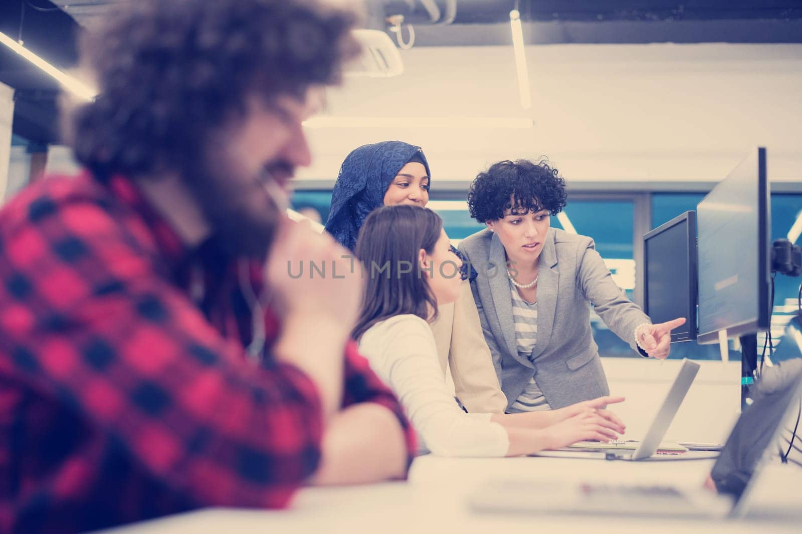 young multiethnics business team of software developers working together using laptop and desktop computer while writing programming code at modern startup office