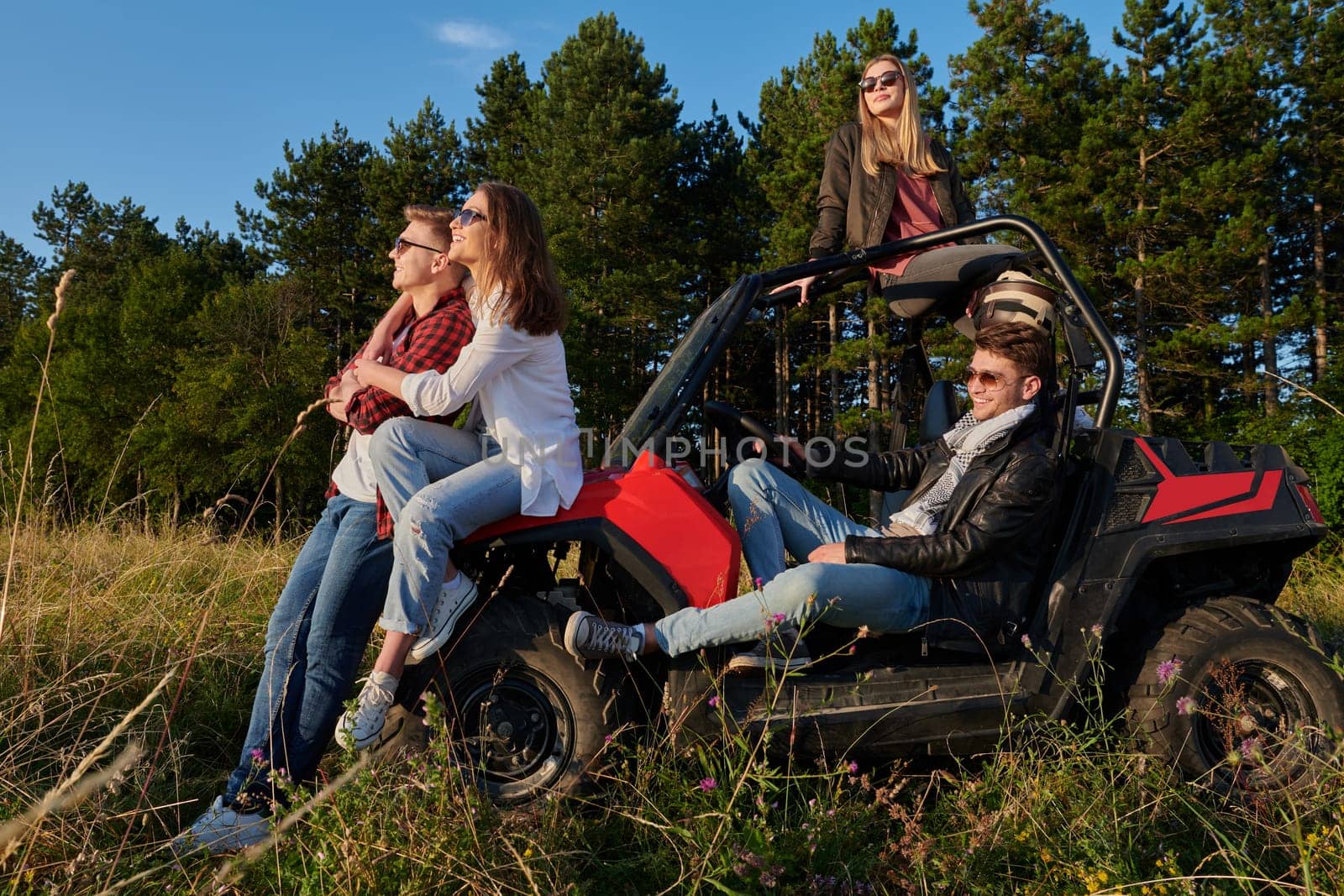 portrait of group young happy people enjoying beautiful sunny day while driving a off road buggy car on mountain nature