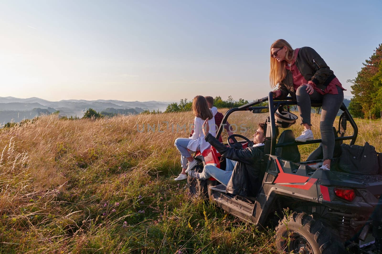 portrait of group young happy people enjoying beautiful sunny day while driving a off road buggy car on mountain nature