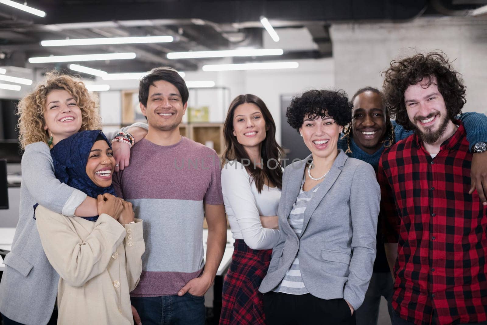 portrait of young excited multiethnics business team of software developers standing and looking at camera while celebrating success at modern startup office