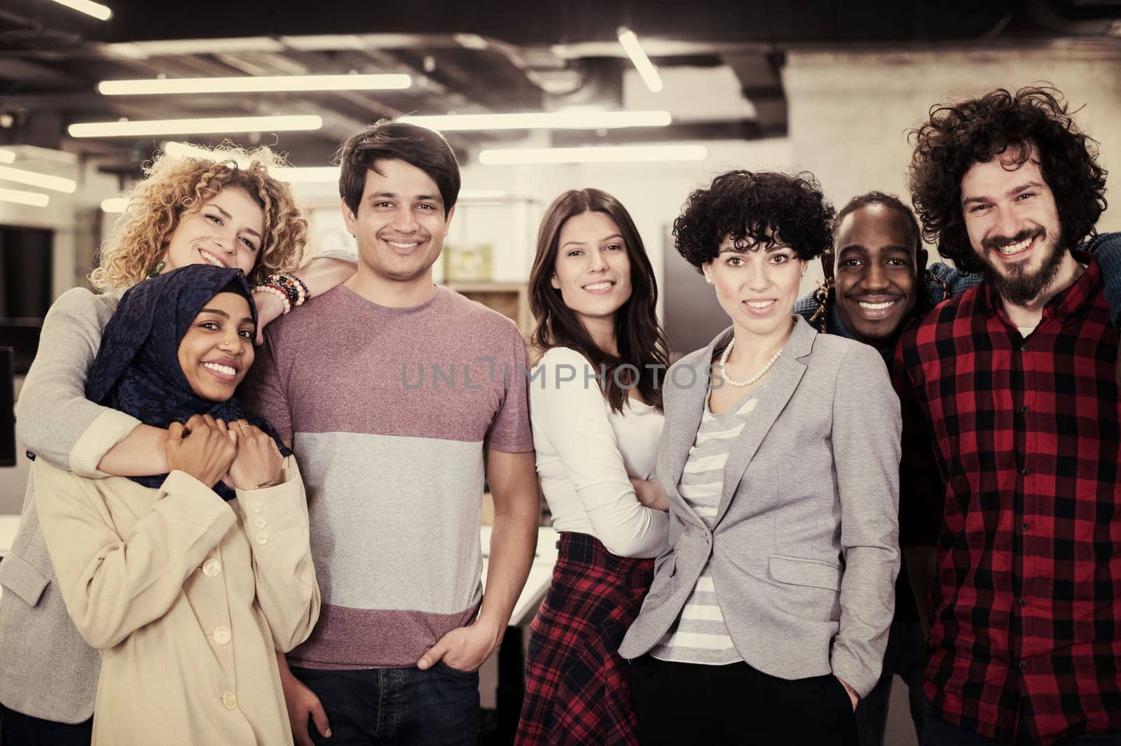 portrait of young excited multiethnics business team of software developers standing and looking at camera while celebrating success at modern startup office