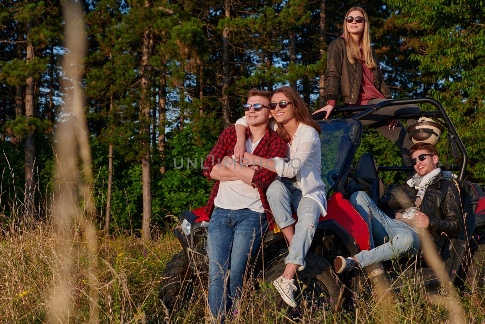 portrait of group young happy people enjoying beautiful sunny day while driving a off road buggy car on mountain nature
