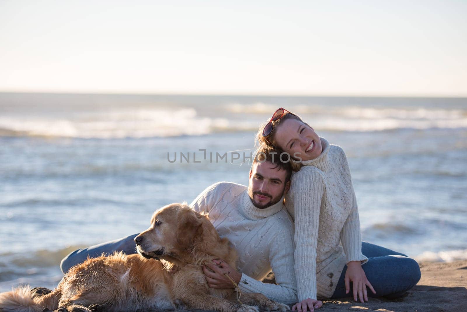 Couple With A Dog enjoying time  together On The Beach at autumn day