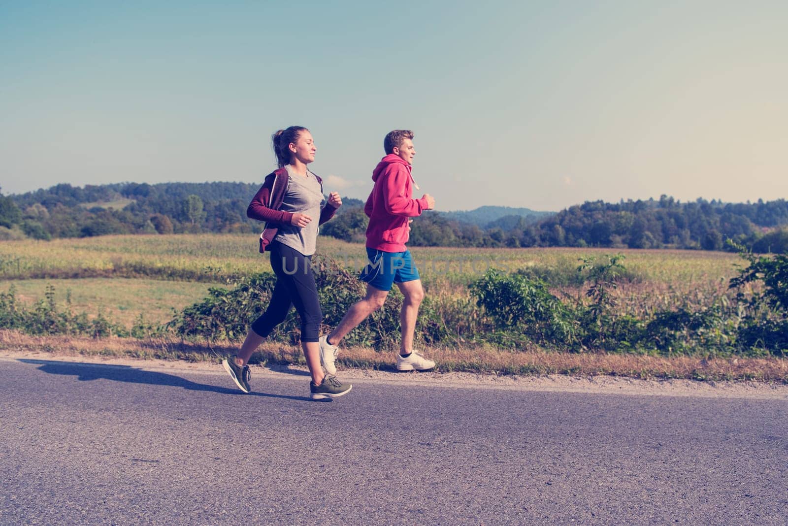 young couple enjoying in a healthy lifestyle while jogging along a country road, exercise and fitness concept