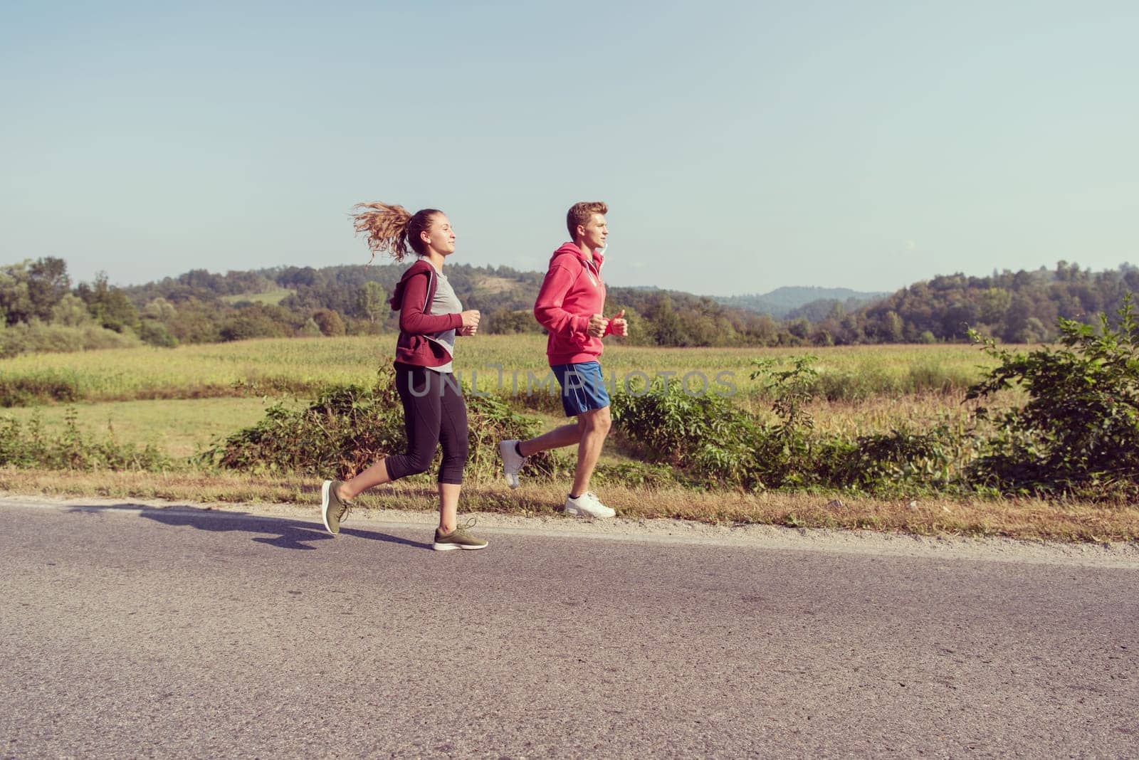 young couple enjoying in a healthy lifestyle while jogging along a country road, exercise and fitness concept