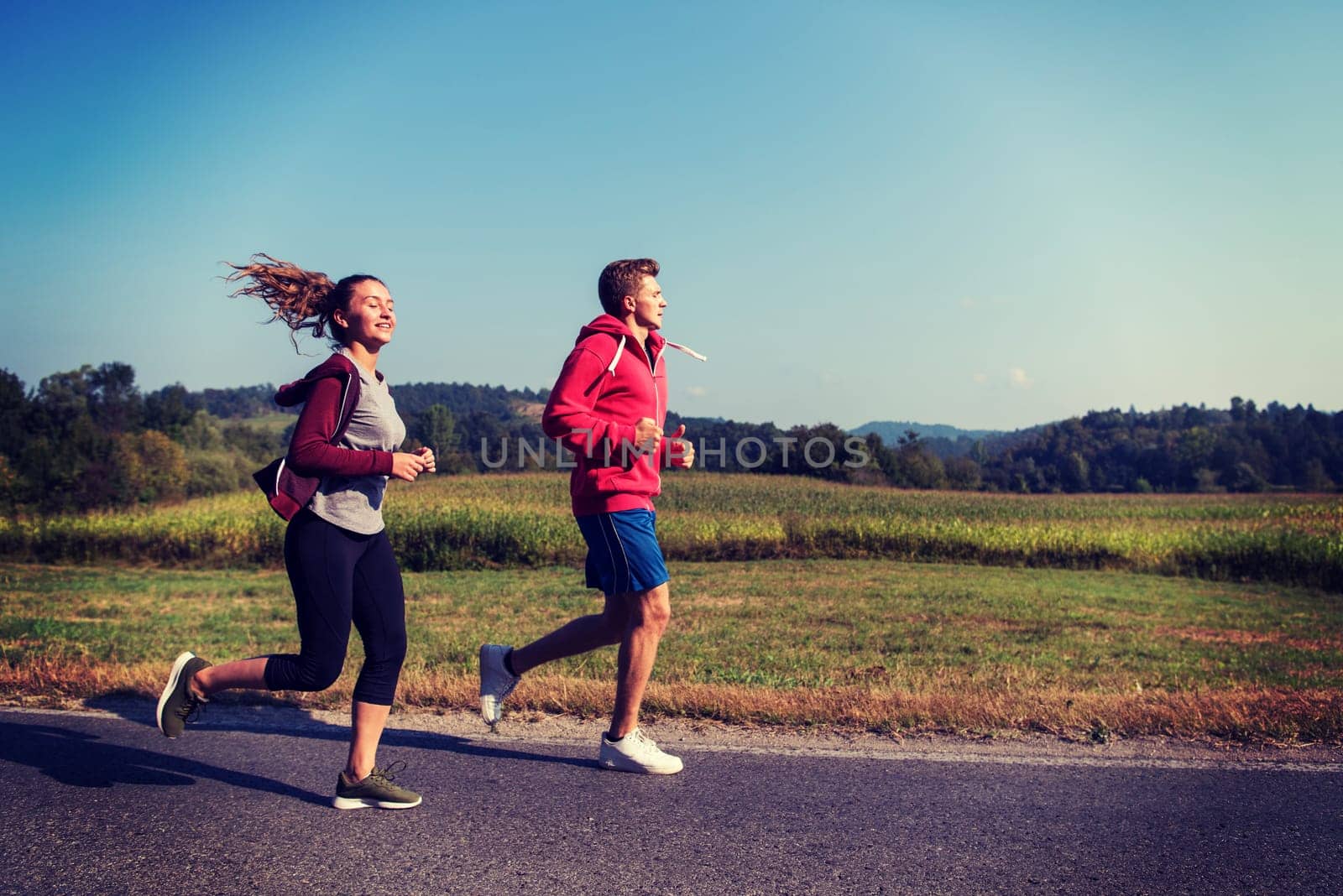 young couple enjoying in a healthy lifestyle while jogging along a country road, exercise and fitness concept